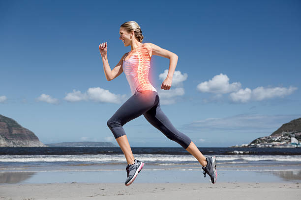 young women running on the beach her spinal column highlighted